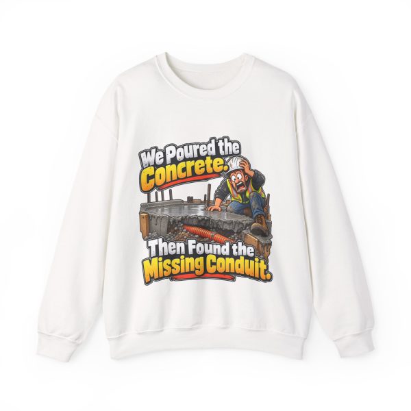 White crewneck sweatshirt printed on the front with a horrified construction worker in a hard hat and hi-vis vest kneeling on a fresh concrete slab, with orange conduit visible buried in the gravel below and the words "We Poured the Concrete. Then Found the Missing Conduit."
