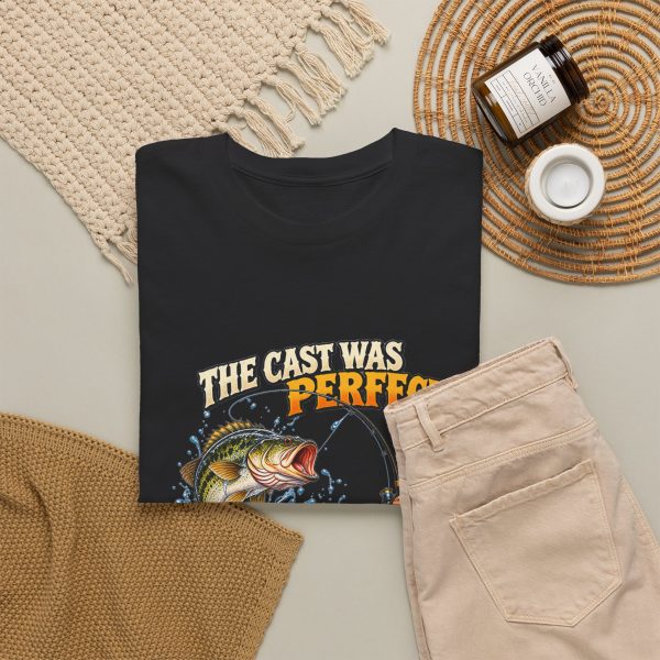 Black T-shirt with "The Cast Was Perfect. The Fish Disagreed." fishing graphic, lifestyle flat-lay