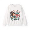 White crewneck sweatshirt printed with "I GET PAID TO BE PEED ON. BARELY." and a tired CNA in teal scrubs giving a thumbs-up