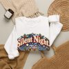 White crewneck sweatshirt with "Silent Night. Until The Pipes Burst" plumber Christmas graphic, lifestyle flat-lay