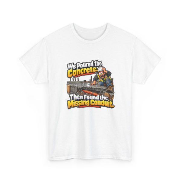 White t-shirt printed on the front with a horrified construction worker in a hard hat and hi-vis vest kneeling on a fresh concrete slab, with orange conduit visible buried in the gravel below and the words "We Poured the Concrete. Then Found the Missing Conduit."