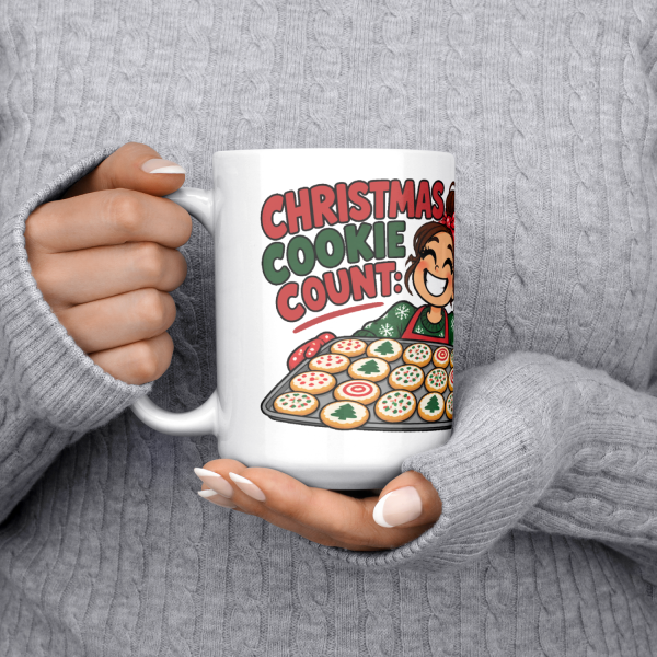15oz white ceramic holiday baker Christmas mug printed with "Christmas Cookie Count: Baked 200. Tested 60.", held at chest