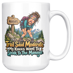 White 15oz ceramic mug with the handle on the right, showing a worn-out hiker clutching her knees beside a wooden MODERATE trail sign, with pine trees and snowy mountains and the words "Trail Said Moderate. My Knees Want To Speak To The Manager."
