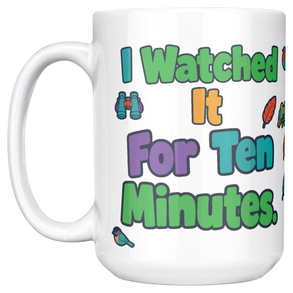 "I watched it for ten minutes. It was a leaf." Birding 15oz mug, handle on the left, first side 15 oz white ceramic birding mug, "I watched it for ten minutes" on one side and "It was a leaf" on the other, with birds, binoculars and leaves, handle on the left, first side