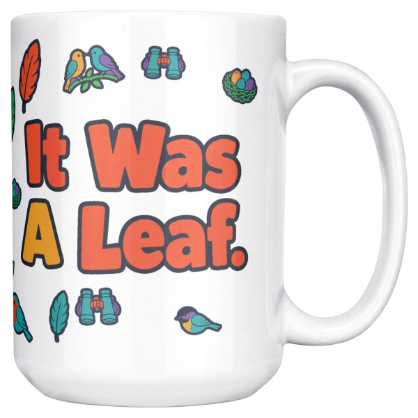 "I watched it for ten minutes. It was a leaf." Birding 15oz mug, handle on the right, second side 15 oz white ceramic birding mug, "I watched it for ten minutes" on one side and "It was a leaf" on the other, with birds, binoculars and leaves, handle on the right, second side