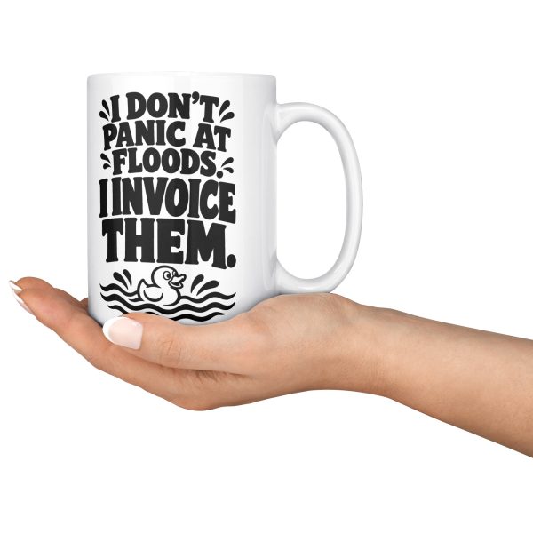 15 oz white ceramic plumber mug printed with "I DON'T PANIC AT FLOODS. I INVOICE THEM.", held in an open hand
