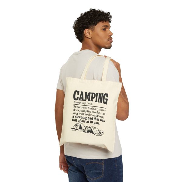 Natural tote bag printed with a black vintage CAMPING dictionary entry ending "a sleeping pad that was full of air at 10 p.m.", carried over the shoulder