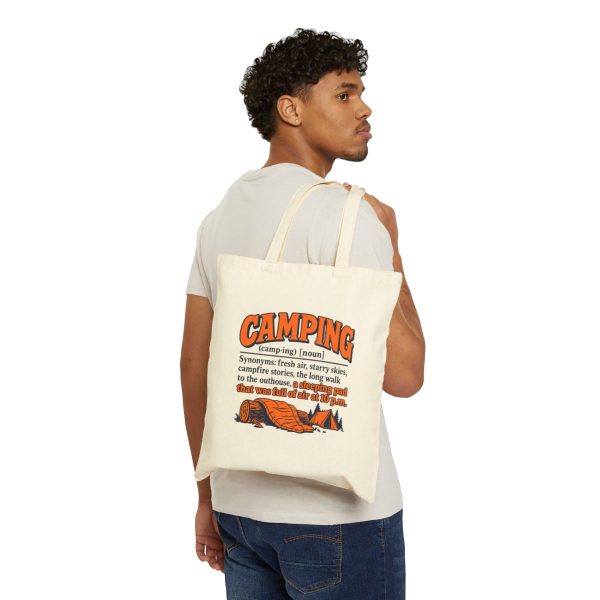 Natural tote bag printed with an orange and navy CAMPING dictionary entry ending "a sleeping pad that was full of air at 10 p.m.", carried over the shoulder