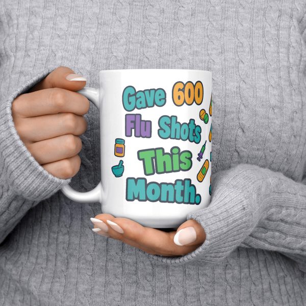 Gave 600 flu shots, still look away, and your team know 15oz mug, held at chest 15 oz white ceramic pharmacist mug, "Gave 600 flu shots this month" on one side and "I still look away at mine" on the other, with pills, bandages and syringes, held at chest