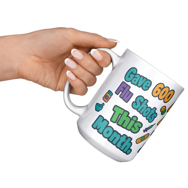 Gave 600 flu shots, still look away, and your team know 15oz mug, raised at an angle 15 oz white ceramic pharmacist mug, "Gave 600 flu shots this month" on one side and "I still look away at mine" on the other, with pills, bandages and syringes, raised at an angle