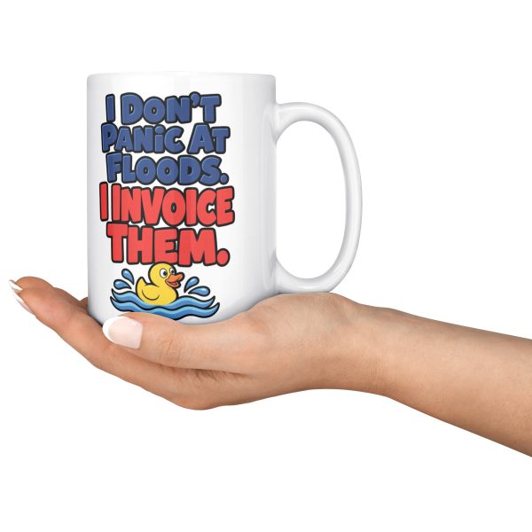 15 oz white ceramic plumber mug printed with "I Don't Panic At Floods. I Invoice Them.", held in an open hand