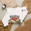 realty-crewneck-i-stage-homes-for-a-living-please-dont-open--4 White crewneck sweatshirt printed with "I Stage Homes for a Living. Please Don't Open My Garage.", styled flat lay