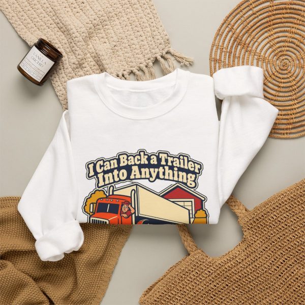 White crewneck sweatshirt printed with "I Can Back a Trailer Into Anything Except My Own Driveway.", styled flat lay