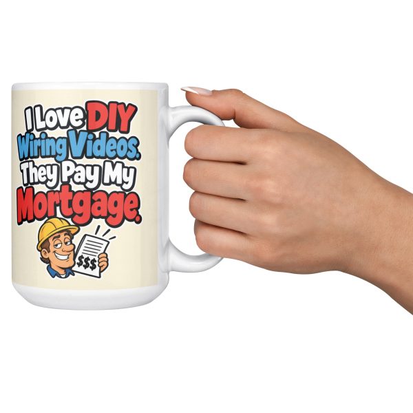15 oz white ceramic electrician mug printed with "I Love DIY Wiring Videos. They Pay My Mortgage.", held out by the handle